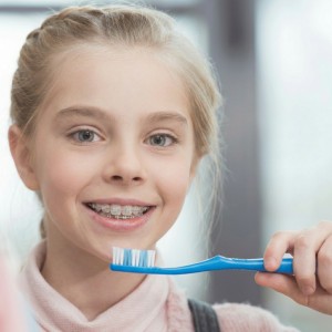 Child with braces brushing teeth, highlighting quality dentistry in Monrovia focused on healthy smiles