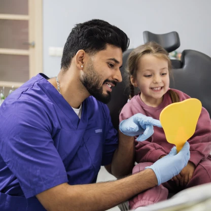 Orthodontist in Monrovia showing a young patient her smile in a hand mirror during a friendly dental visit
